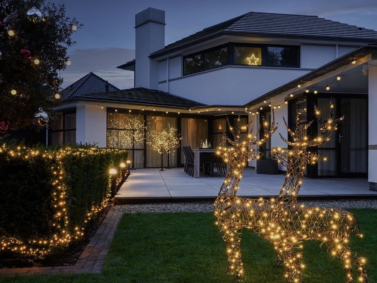 Holiday lights on a home with lit reindeer in the yard