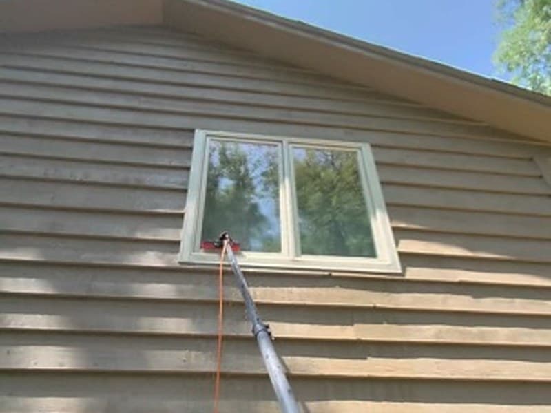Washing the siding of a house from the ground with an extension pole
